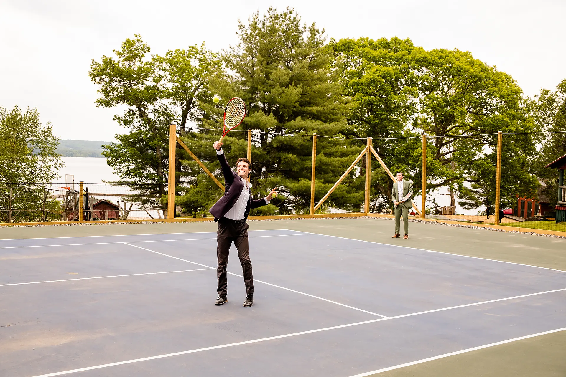 A man reaches his tennis racket up to hit a ball at the Kingsley Pines Camp In Raymond, Maine.