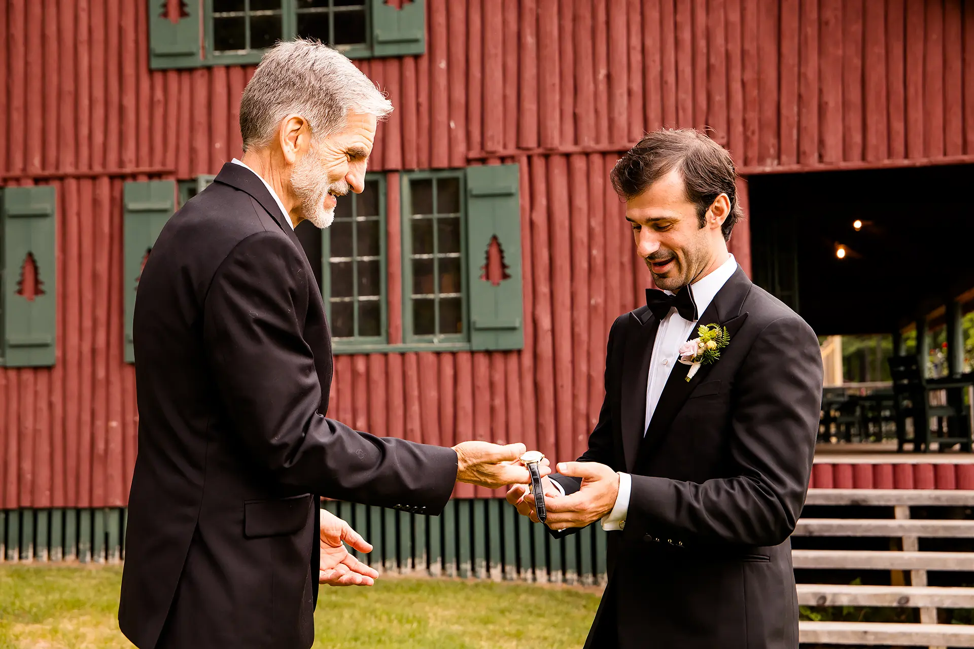 A dad hands a groom a watch as he gets ready for his wedding at Kingsley Pines Camp in Raymond, Maine.