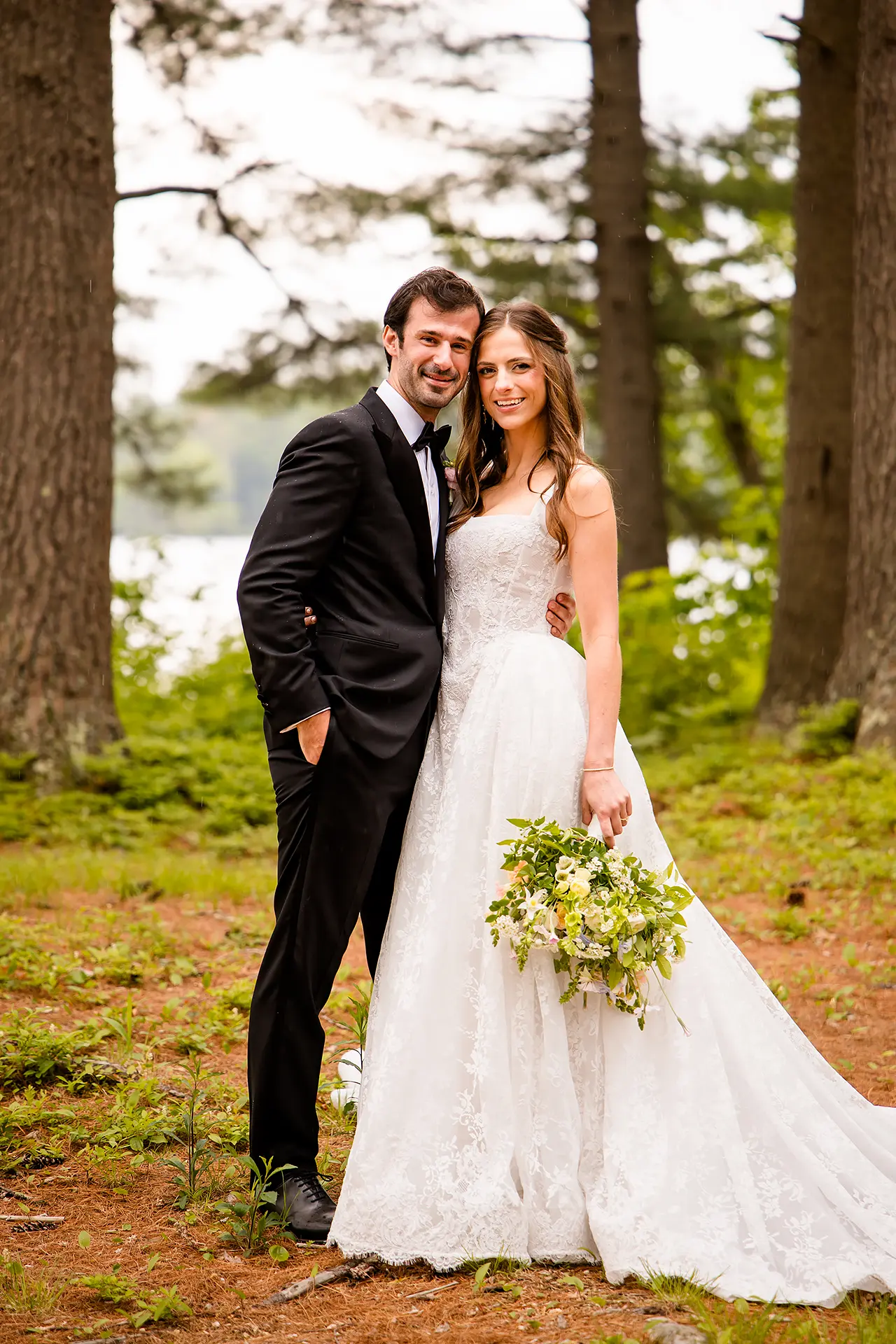 A bride and groom smile and pose during wedding portraits at Kingsley Pines Camp in Raymond, Maine.