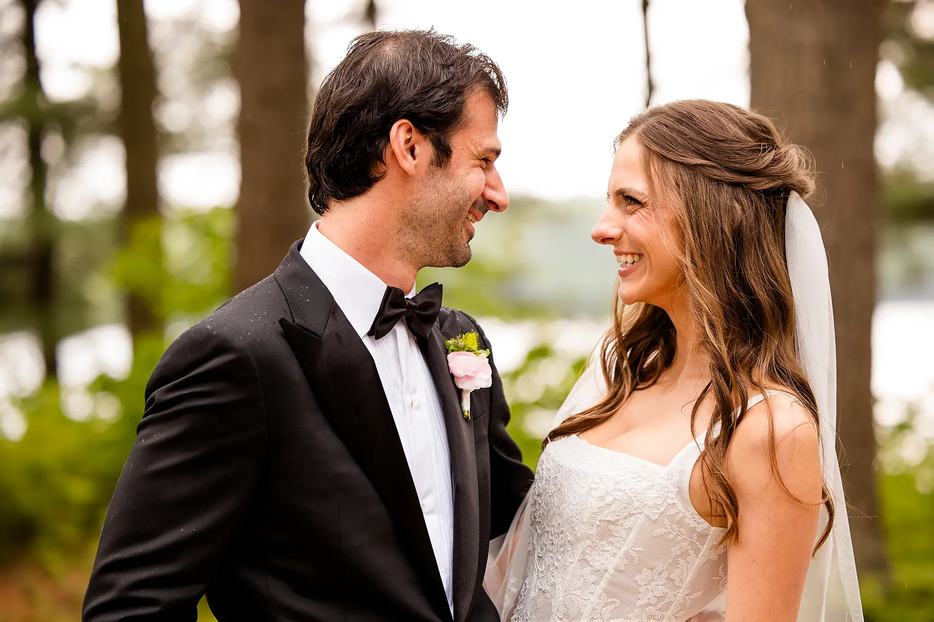 A bride and groom laugh as they look at each other during wedding portraits at Kingsley Pines Camp in Raymond, Maine.