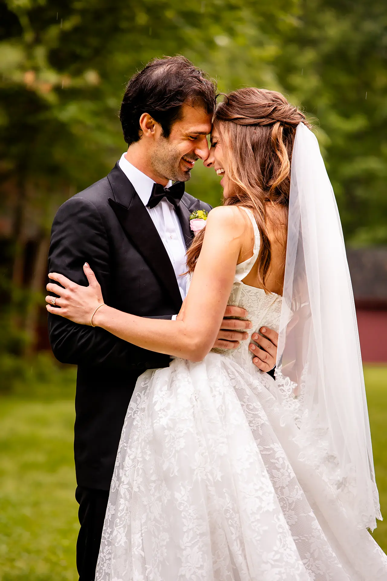 A bride and groom hold each other and laugh during wedding portraits at Kingsley Pines Camp in Raymond, Maine.