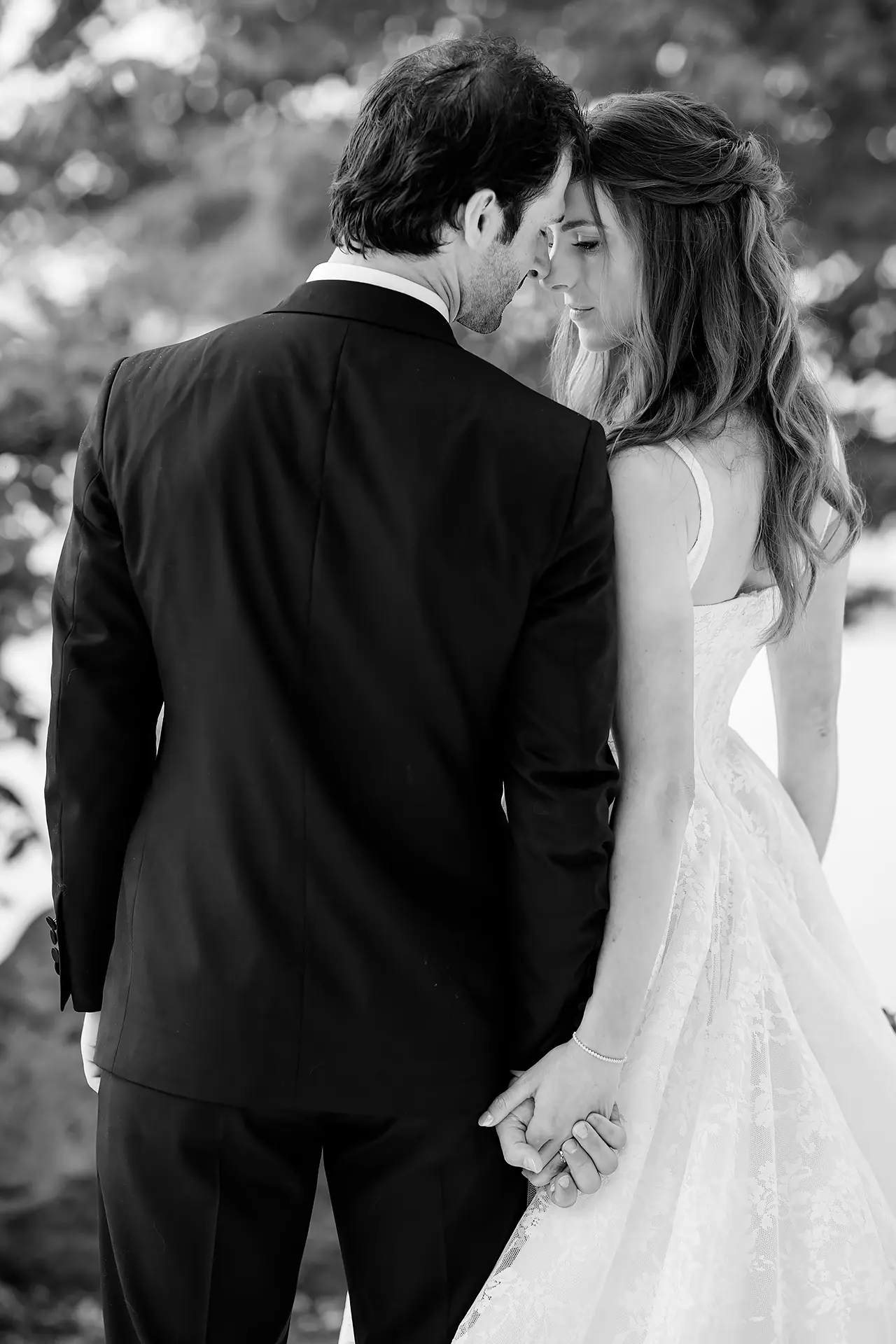 A bride and groom hold hands and rest their heads together during wedding portraits at Kingsley Pines Camp in Raymond, Maine.