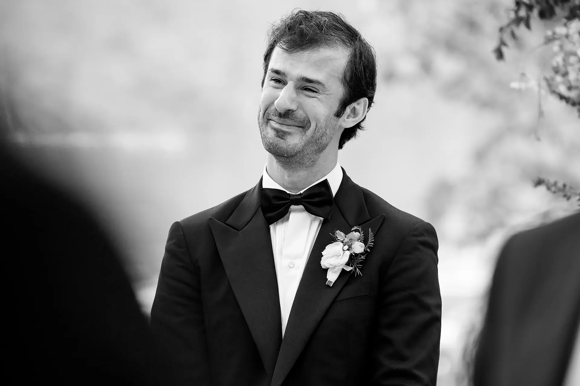 A groom smiles as he watches a bride walk down the aisle during a wedding ceremony at Kingsley Pines Camp in Raymond, Maine.