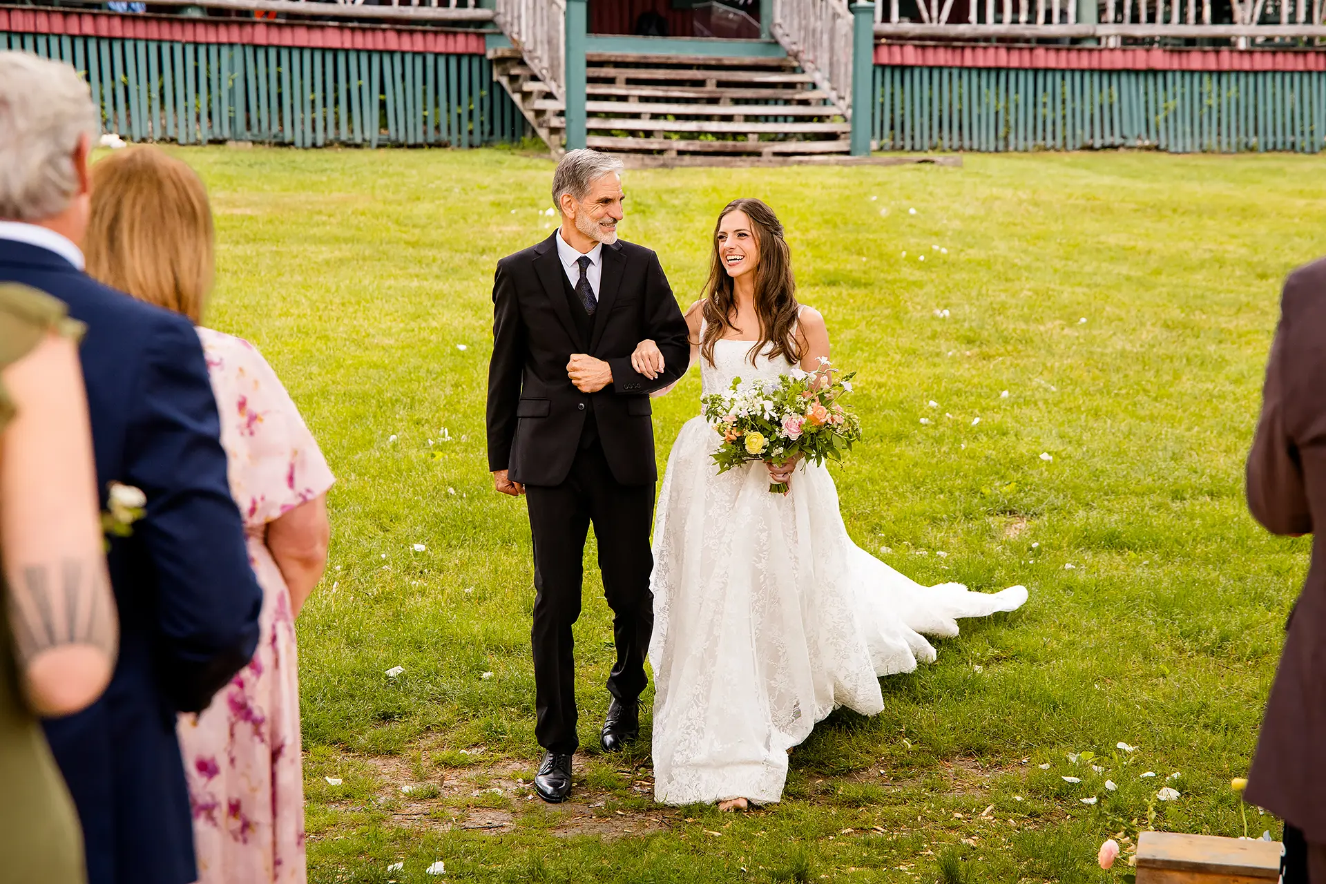 A bride and her dad smile as they walk down the aisle during a wedding ceremony at Kingsley Pines Camp in Raymond, Maine.