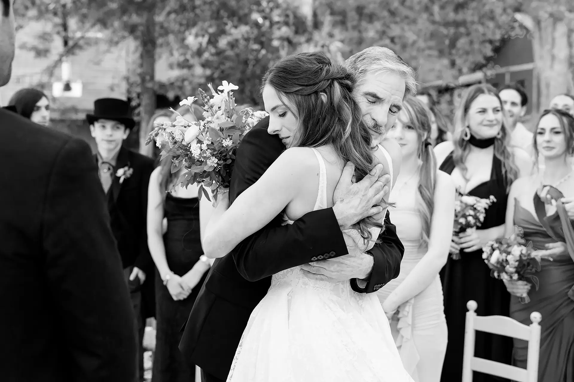 A bride hugs her dad as guests watch during a wedding ceremony at Kingsley Pines Camp in Raymond, Maine.