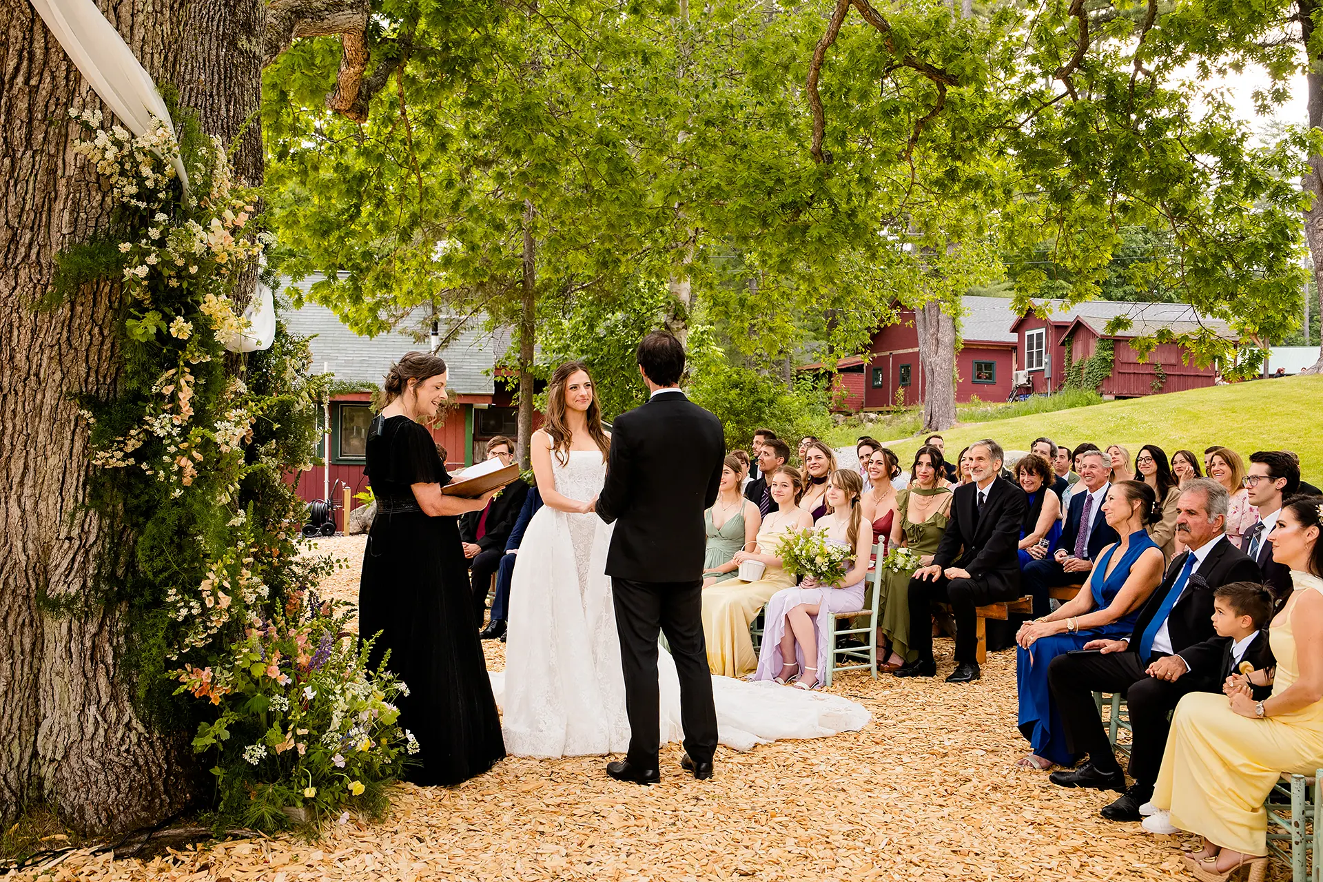 A bride smiles as she hold a groom's hands during a wedding ceremony at Kingsley Pines Camp in Raymond, Maine.