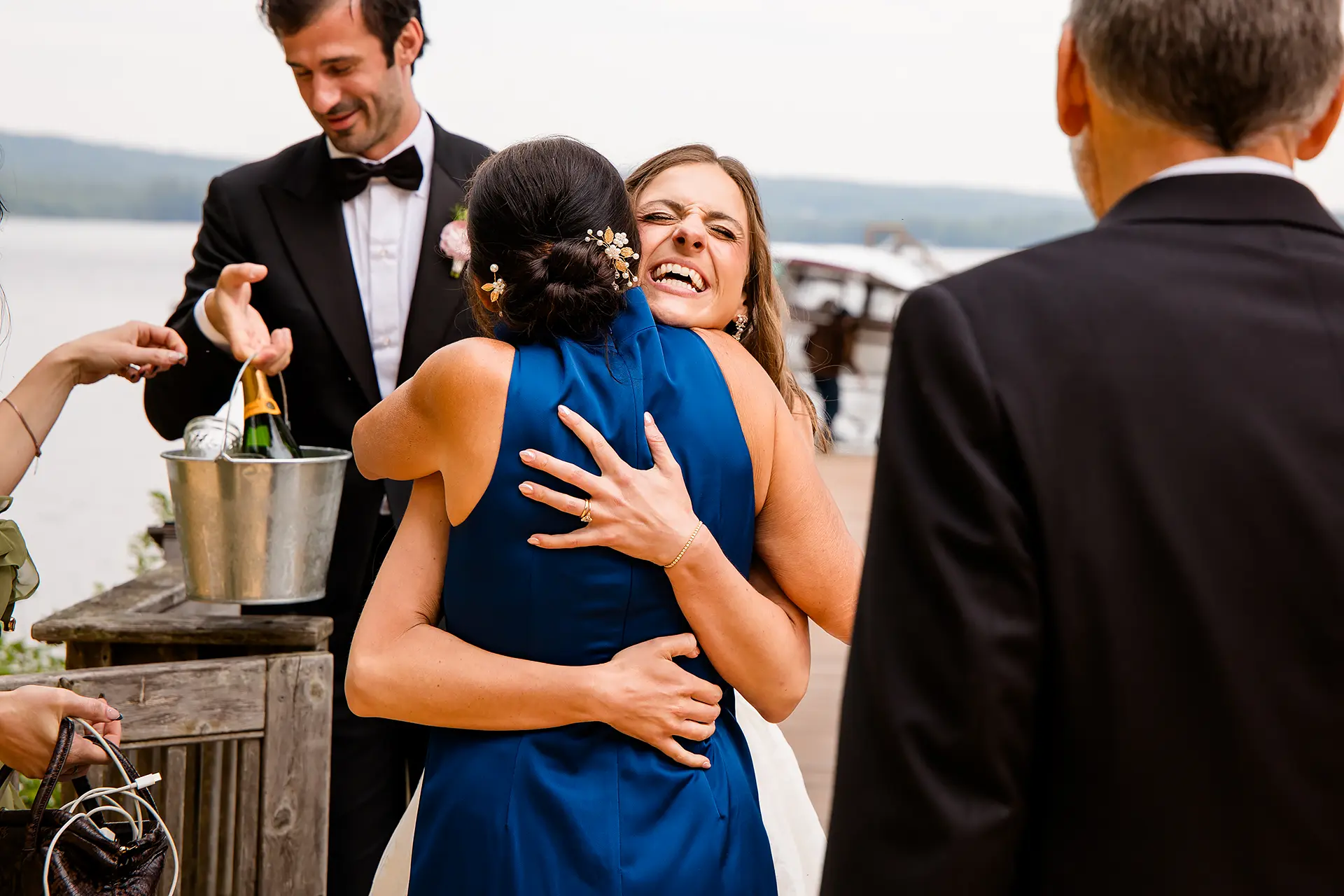 A bride laughs as she hugs a mom during a wedding at Kingsley Pines Camp in Raymond, Maine.