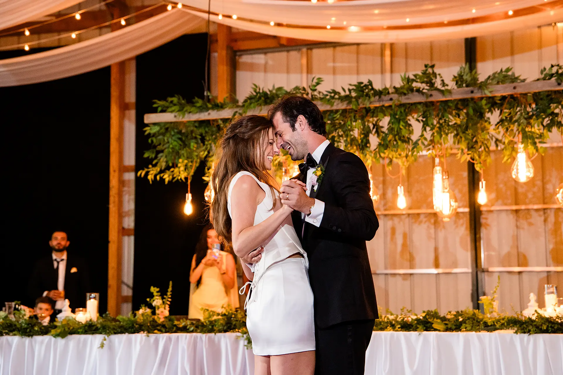 A bride and groom rest their heads together and laugh during their first dance at Kingsley Pines Camp in Raymond, Maine.