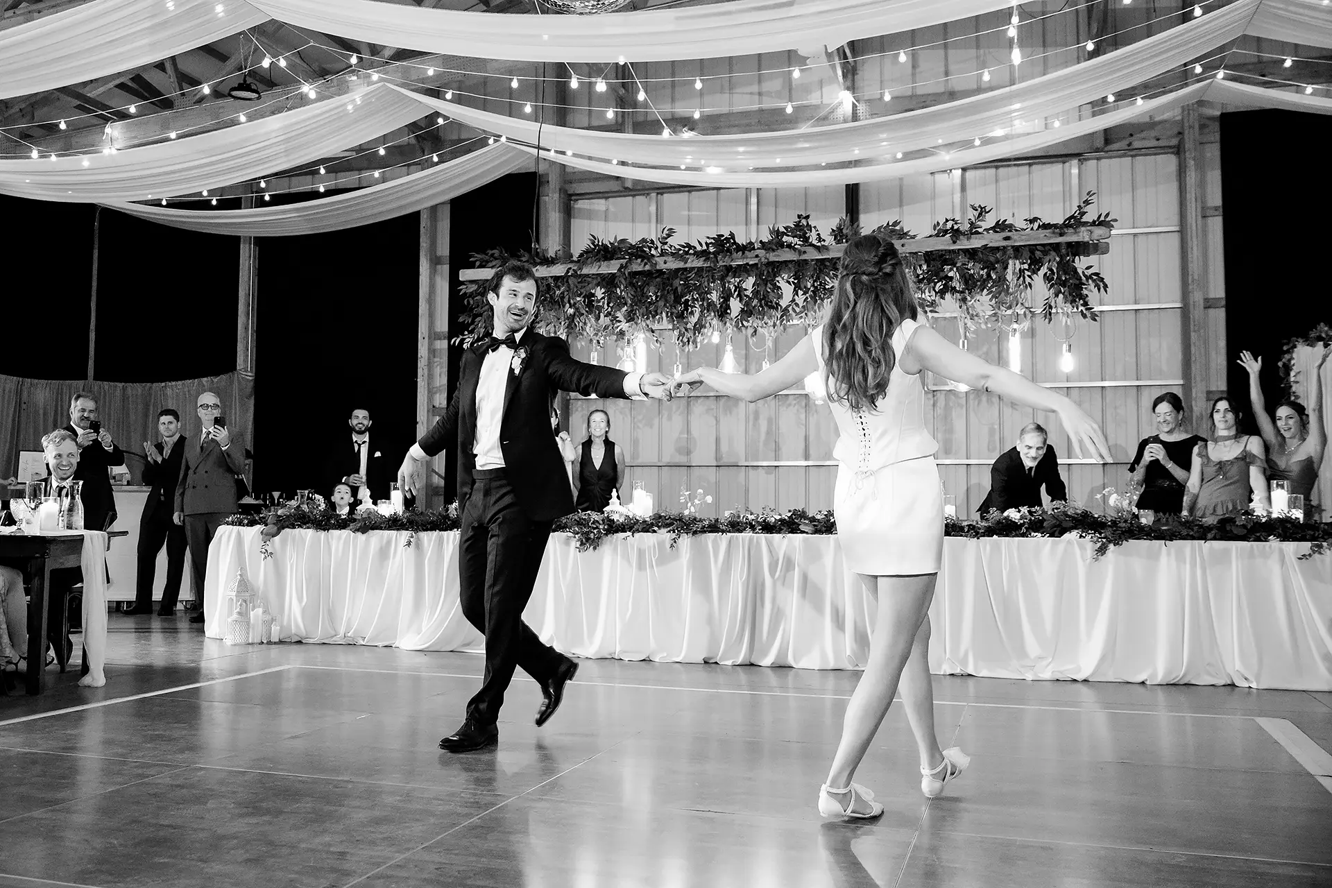 A groom hold a bride's hand and laughs as they dance during a wedding reception at Kingsley Pines Camp in Raymond, Maine.