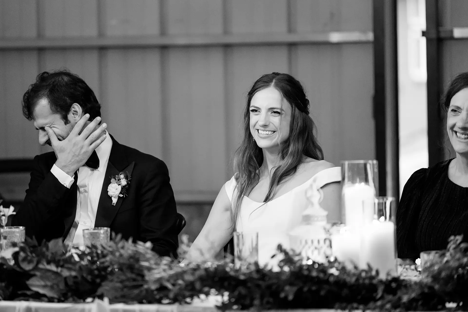 A bride smiles while a groom cries as they listen to a toast during a wedding reception at Kingsley Pines Camp in Raymond, Maine.
