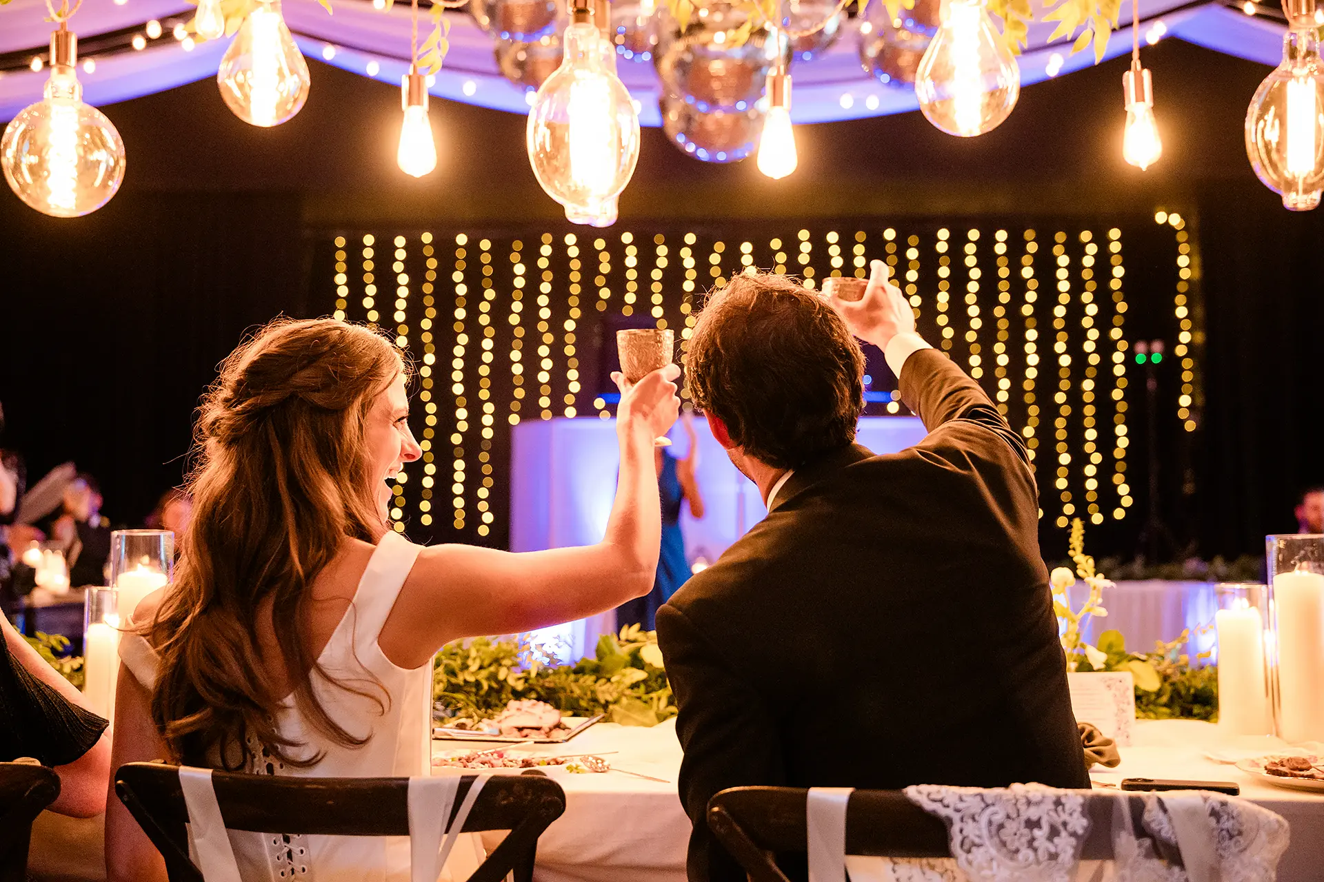 A bride and groom raise their glasses to toast during a wedding reception at Kingsley Pines Camp in Raymond, Maine.