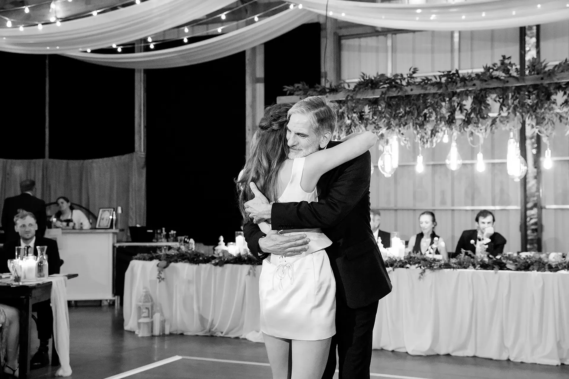 A dad hugs a bride as they share a dance during a wedding reception at Kingsley Pines Camp in Raymond, Maine.