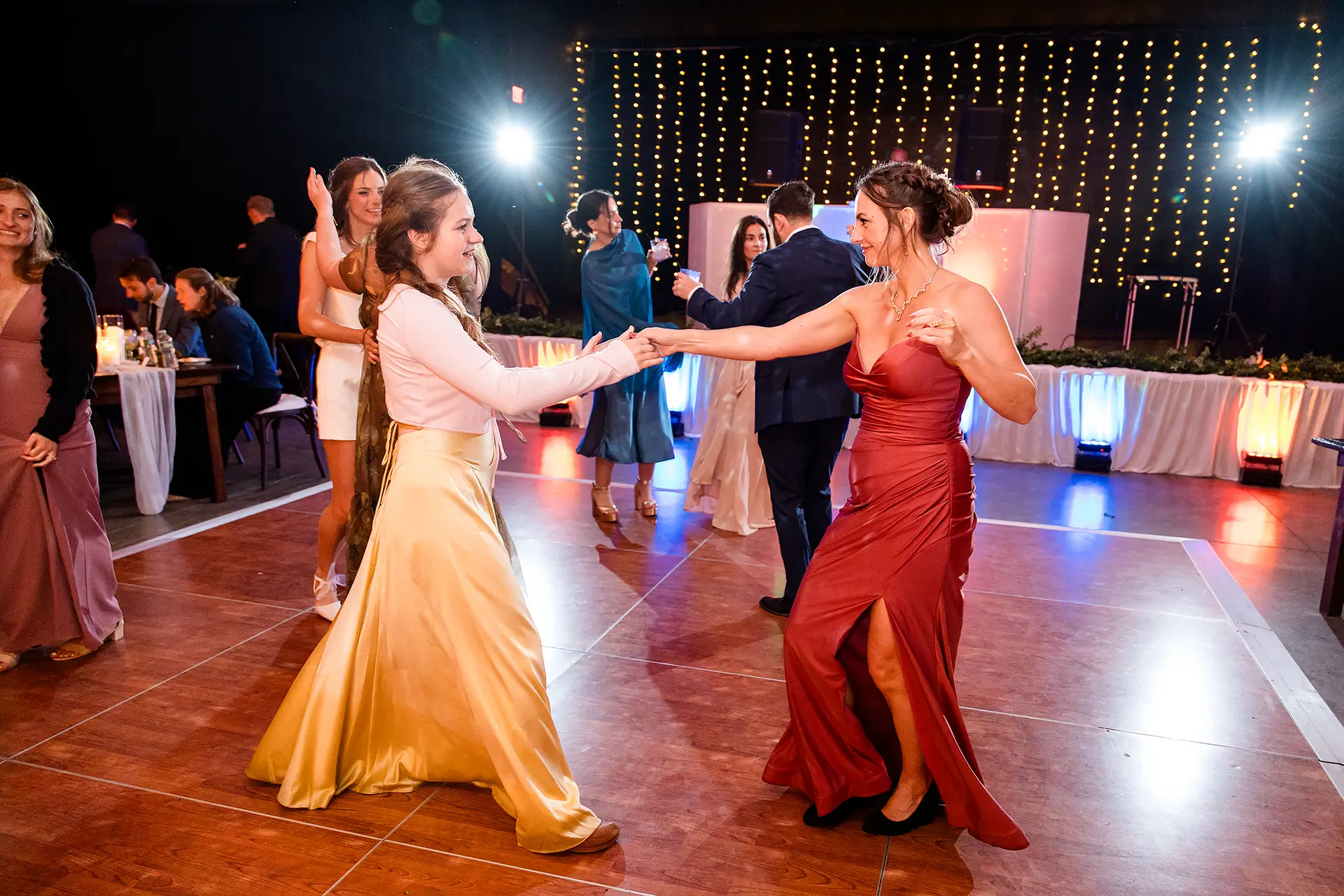 A bridesmaid and a guest dance during a wedding reception at Kingsley Pines Camp in Raymond, Maine.