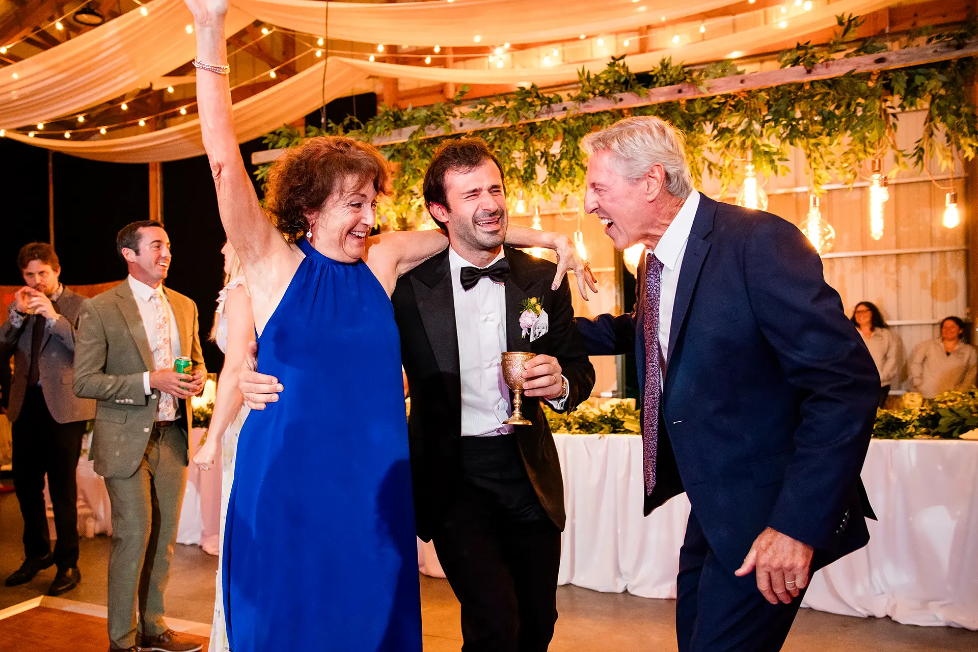 A wedding guests dance with a groom during a wedding reception at Kingsley Pines Camp in Raymond, Maine.