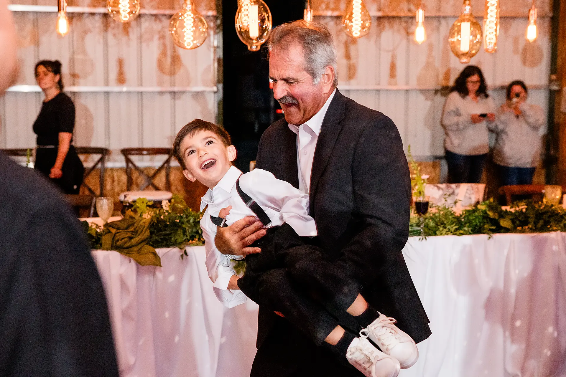 A man spins a young boy as they dance during a wedding reception at Kingsley Pines Camp in Raymond, Maine.