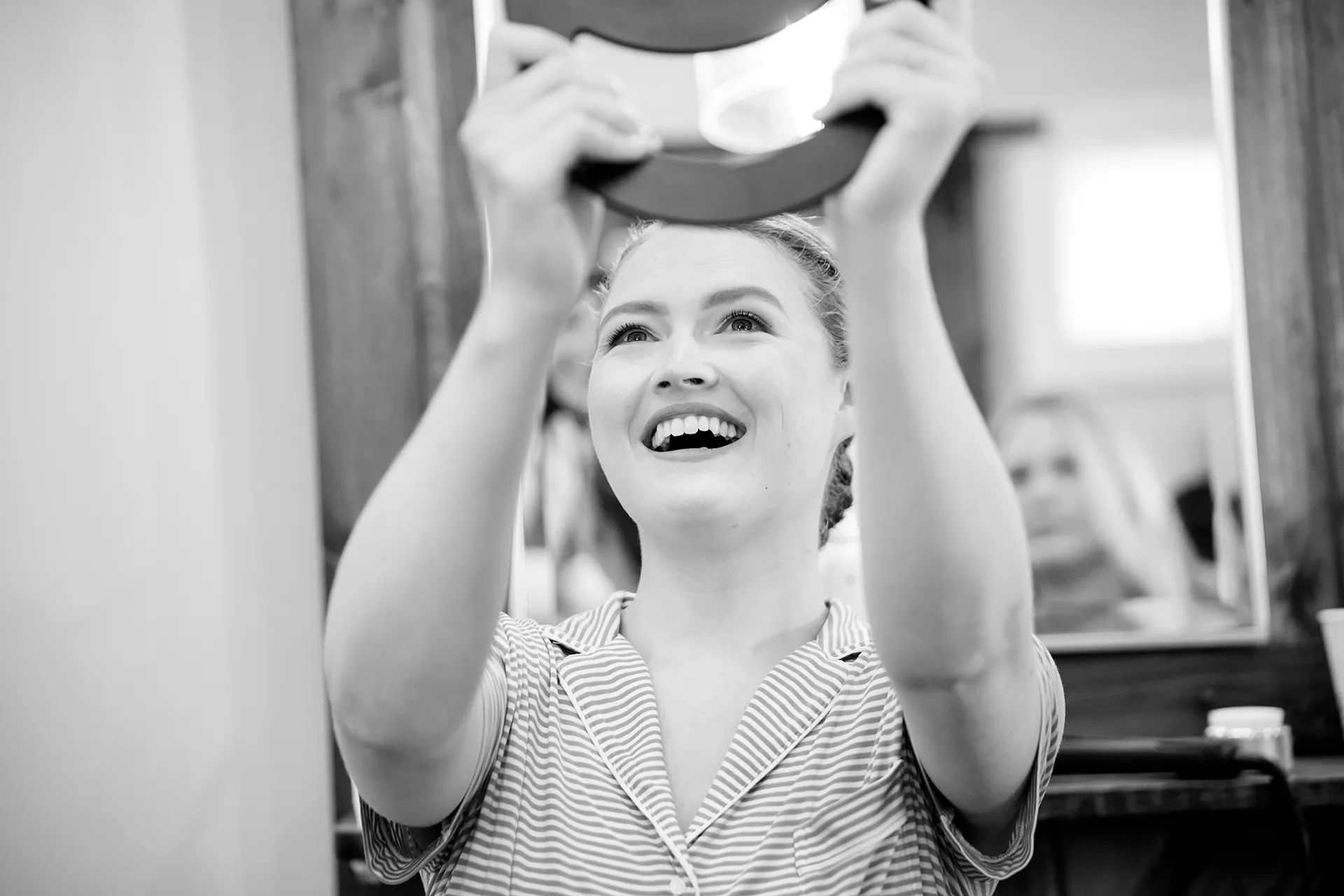 A bride smiles as she looks at herself in the mirror as she gets ready for her wedding at the Nonantum Resort in Kennebunkport, Maine.