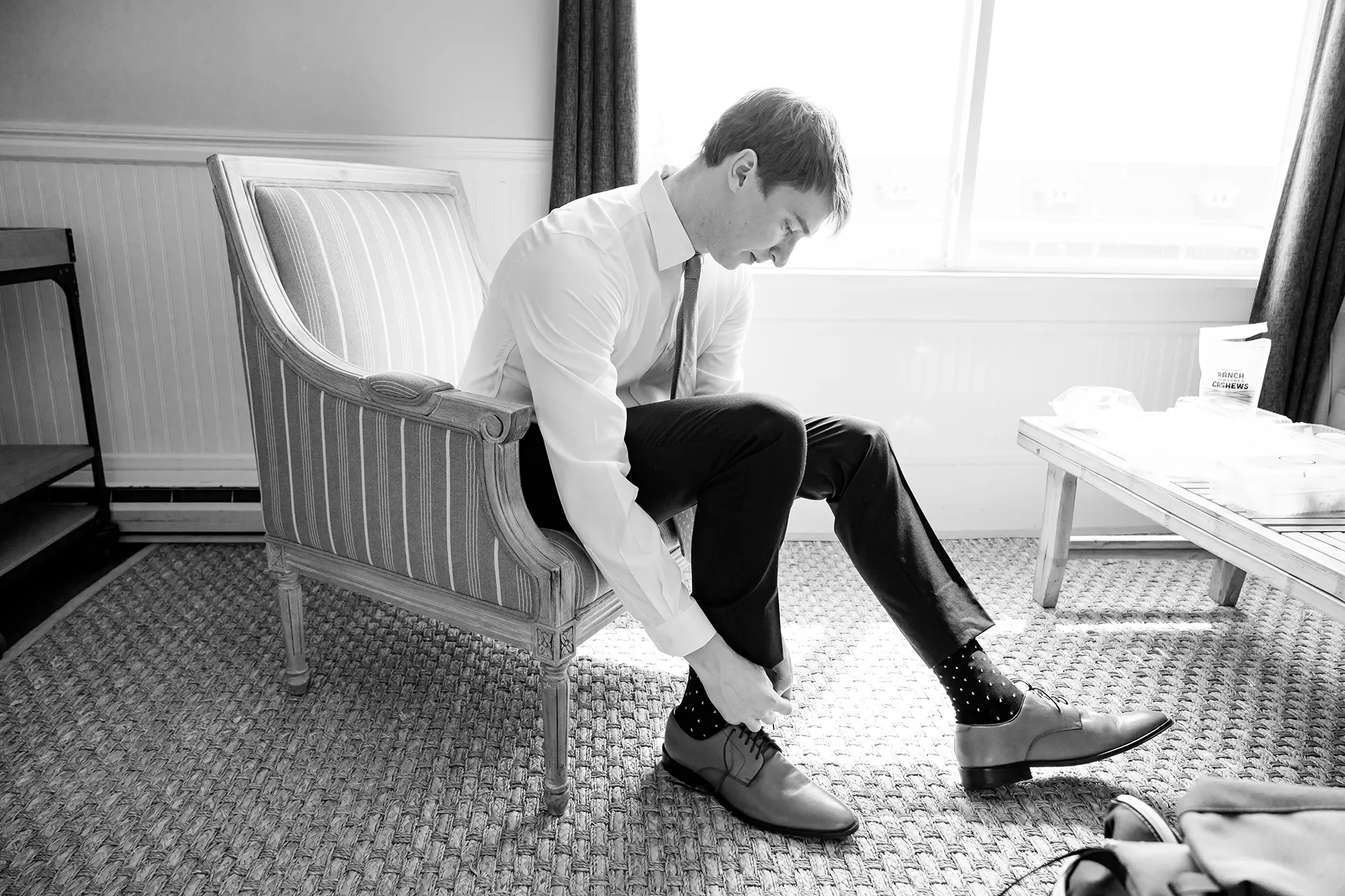 A groom ties his shoes as he gets ready for a wedding at the Nonantum Resort in Kennebunkport, Maine.