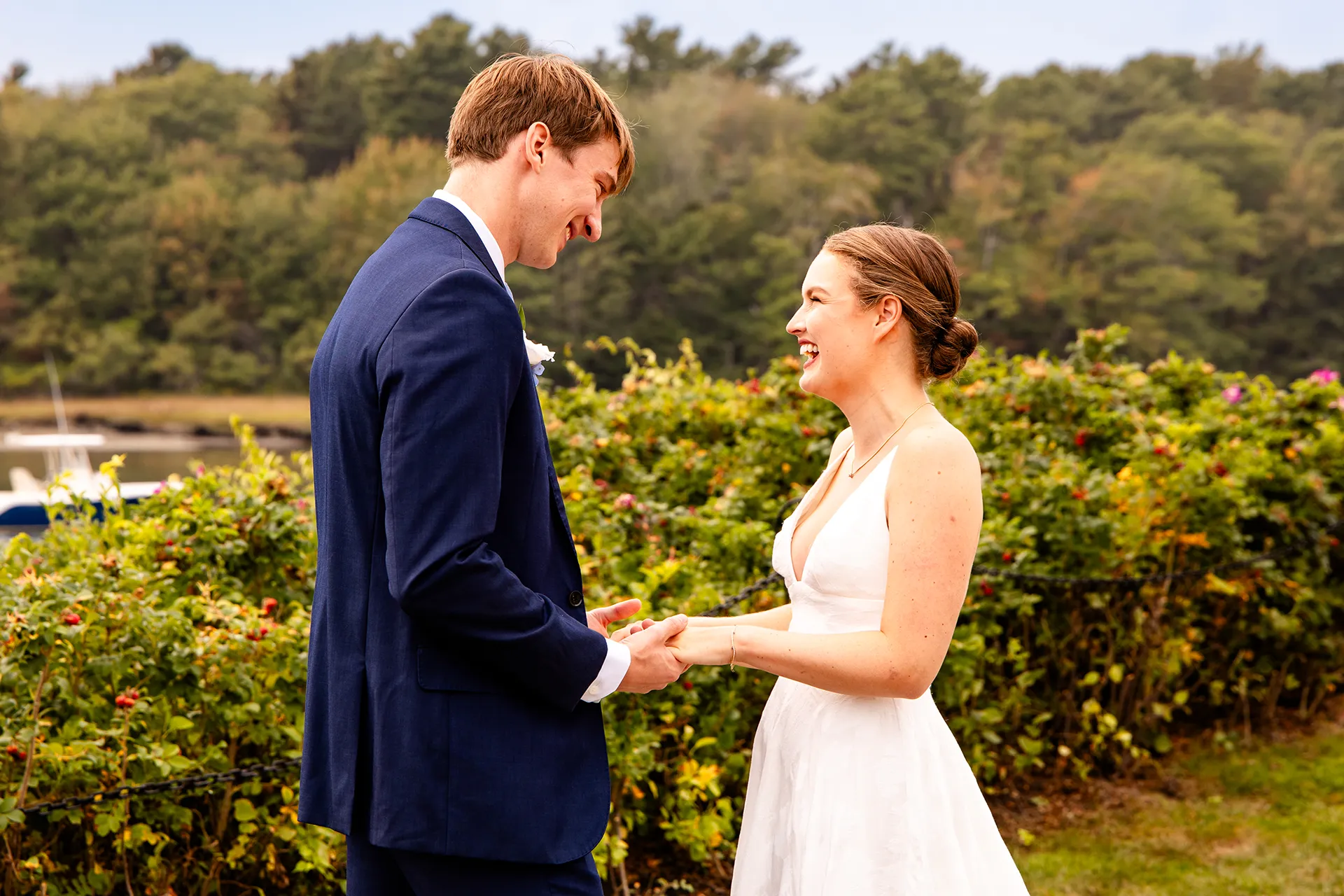 A bride and groom hold hands as they smile at each other during wedding portraits at the Nonantum Resort in Kennebunkport, Maine.