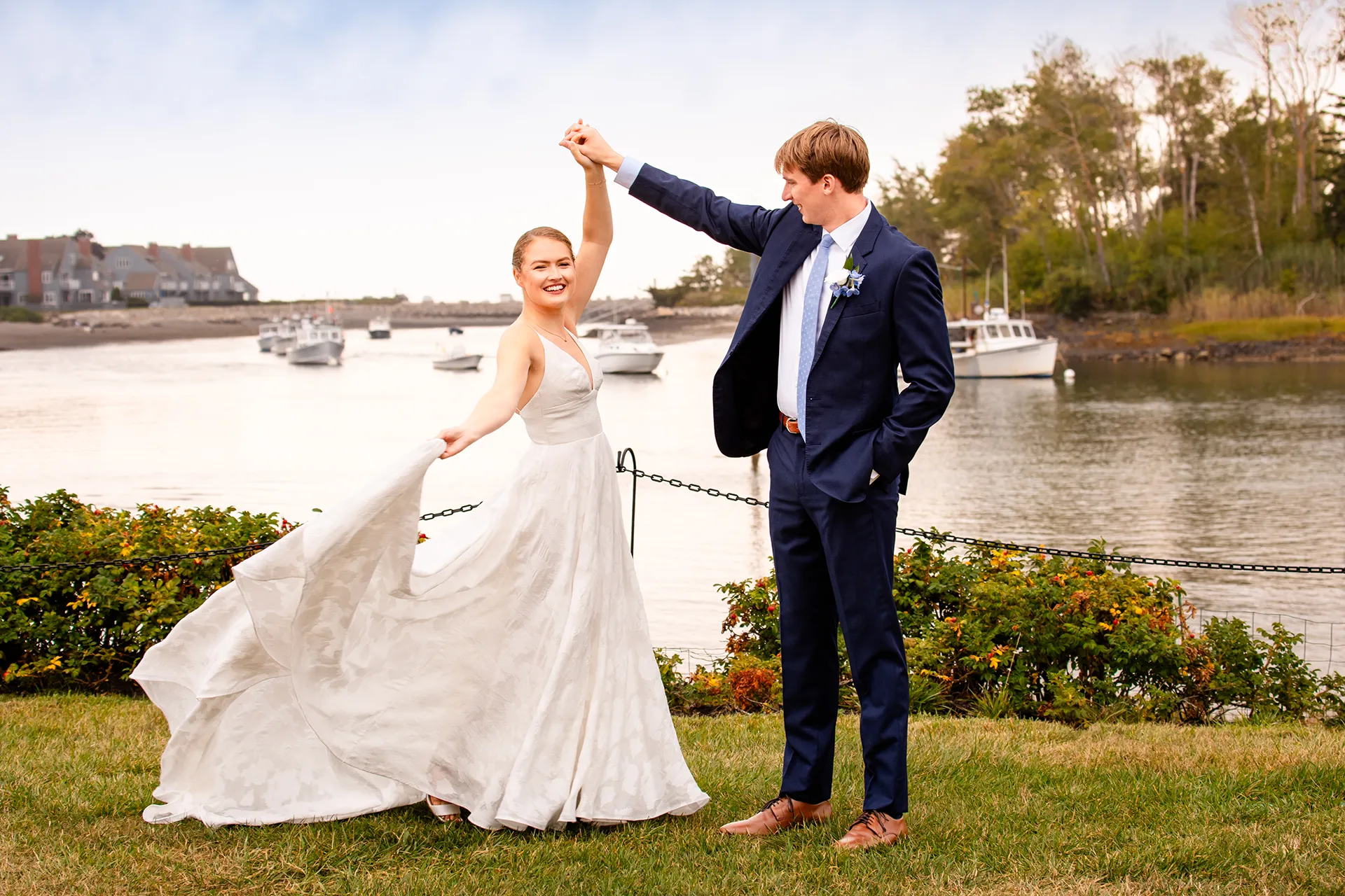 A smiling bride spins as a groom hold her hand during wedding portraits at the Nonantum Resort in Kennebunkport, Maine.