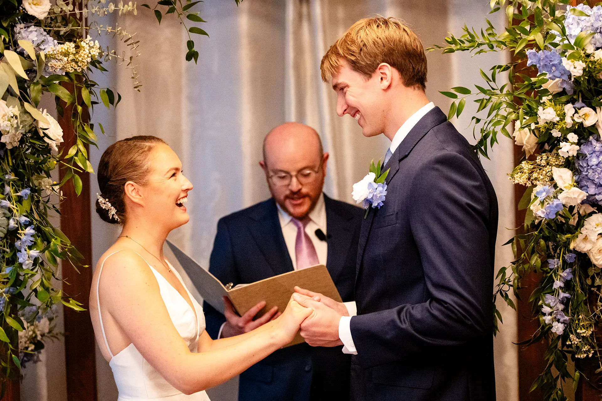 A bride and groom hold hands and laugh during a wedding ceremony at the Nonantum Resort in Kennebunkport, Maine.