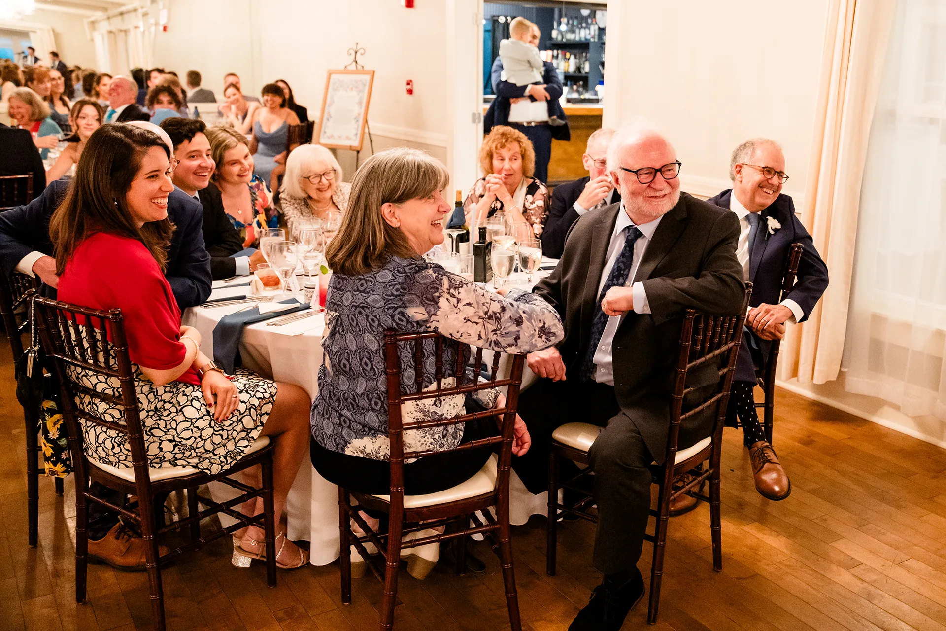 Guests smile as they listen to a toast during a wedding reception at the Nonantum Resort in Kennebunkport, Maine.