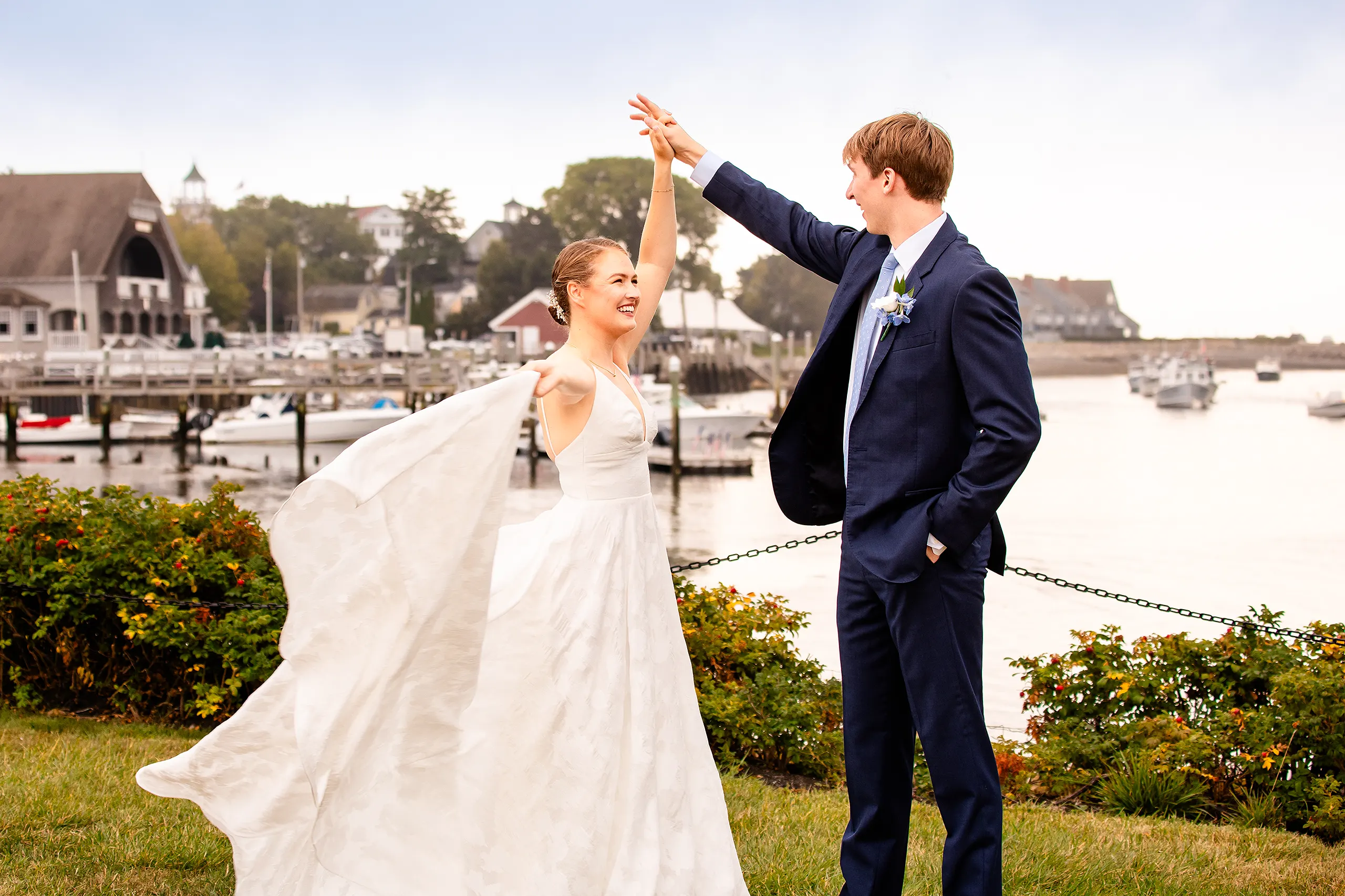 A bride twirls her dress as a groom hold her hand during wedding portraits at the Nonantum Resort in Kennebunkport, Maine.