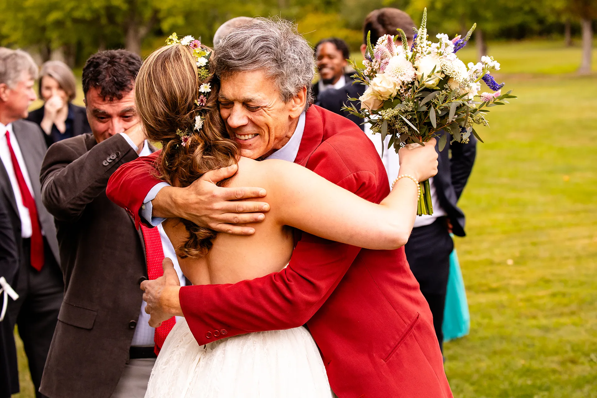 A smiling man hugs a bride during a summer wedding reception in Bangor, Maine.